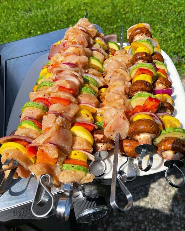 several skewers filled with meat and vegetables on a bbq grill in the grass