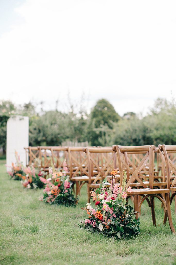 rows of wooden benches lined up in the grass with flowers on each seat and one bench at the end