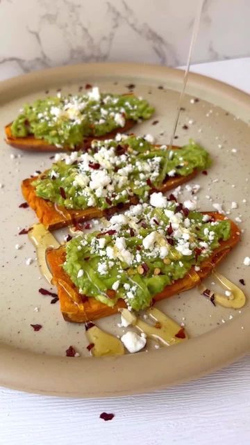 two pieces of toast topped with green sauce and feta cheese on a brown plate