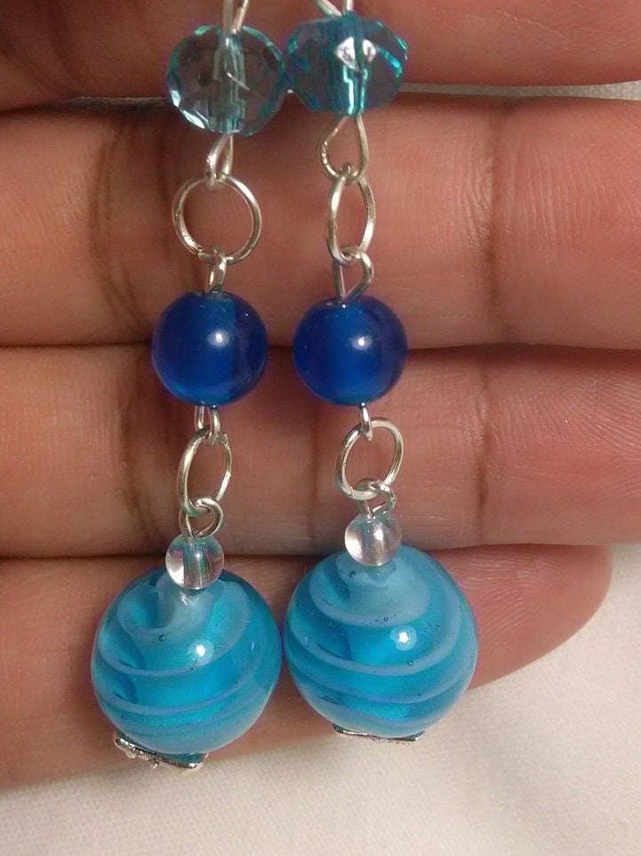 These earrings reminds me of the Caribbean Sea and wishing I was on a vacation. The earrings made with 10mm ocean blue glass beads, 2mm blue beads and 2 mm Czech beads. Perfect for any occasion. Blue Earrings With Colorful Round Beads, Blue Czech Glass Beaded Earrings Wire Wrapped, Blue Round Beaded Earrings, Blue Czech Glass Wire Wrapped Beaded Earrings, Blue Earrings With Dangling Round Beads, Blue Czech Glass Beaded Earrings, Blue Round Beaded Earrings For Beach, Blue Beaded Earrings For Beach, Blue Wire Wrapped Round Bead Earrings