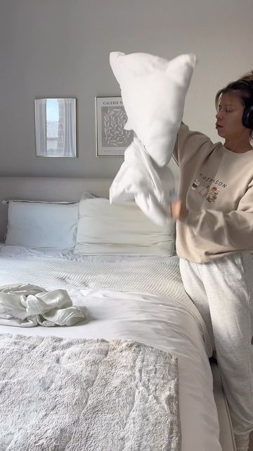 a woman is jumping on the bed with pillows