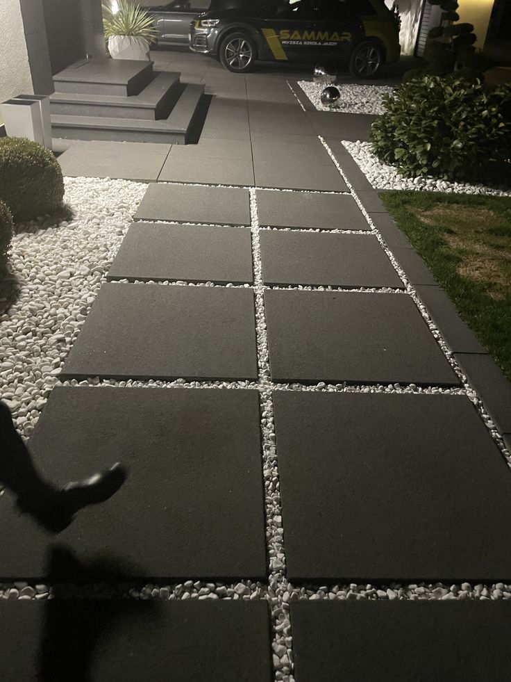 a black and white photo of someone's feet walking down the sidewalk in front of their house