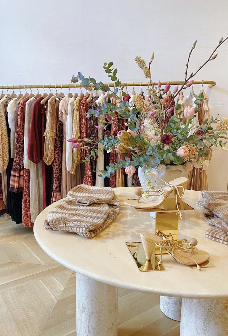 a table that has some clothes on it and flowers in the vase next to it