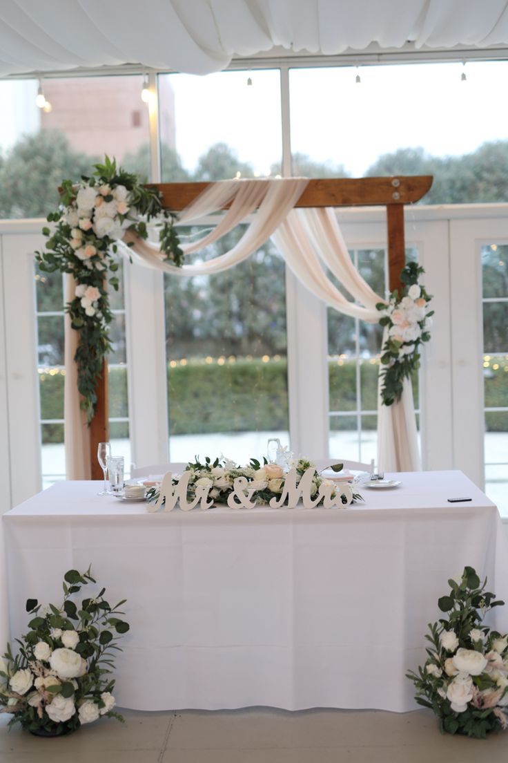 the table is set up with white flowers and greenery for an elegant wedding reception