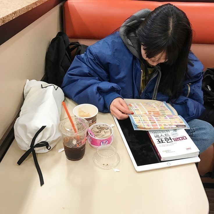 a woman sitting at a table looking at a magazine