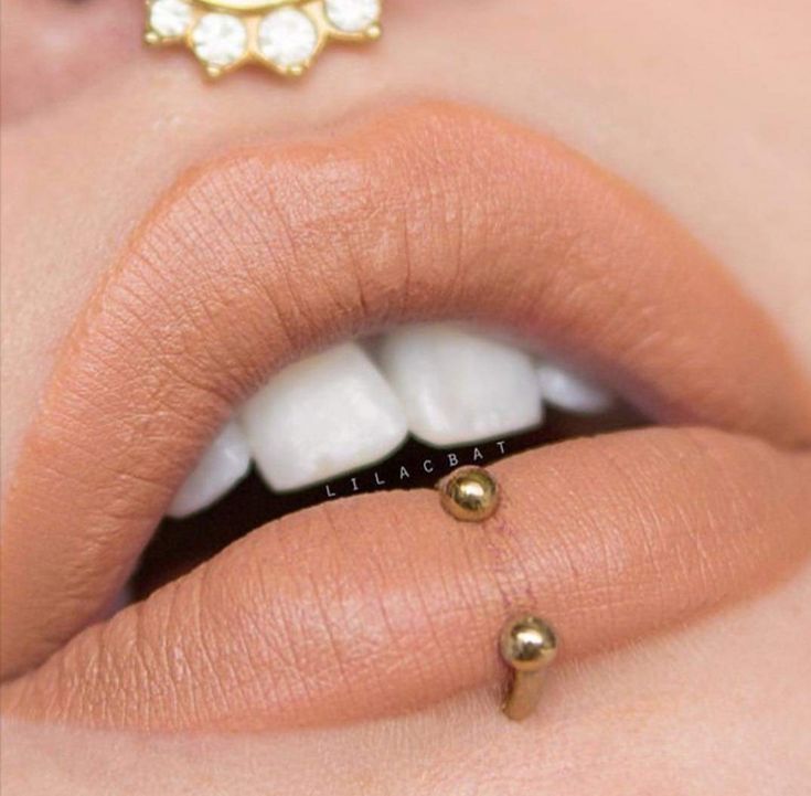 a close up shot of a woman's lips with gold nose piercings