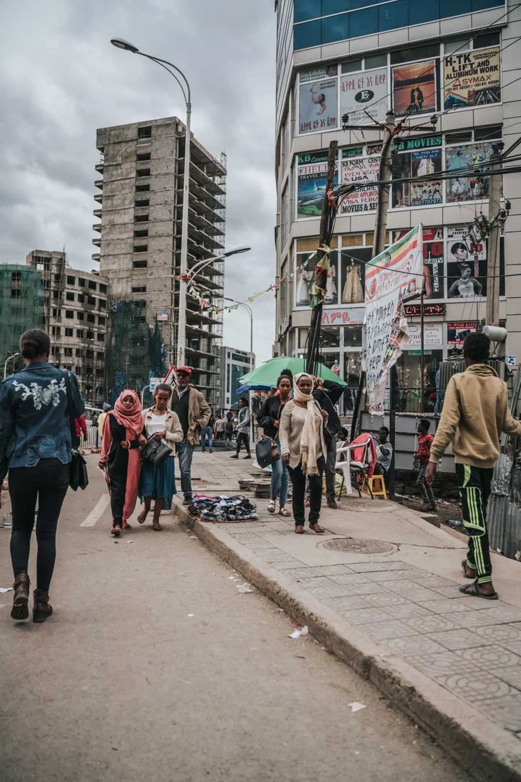 people walking down the street with umbrellas and signs on buildings in the background,