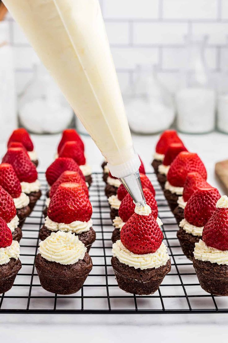 someone is decorating cupcakes with strawberries and cream