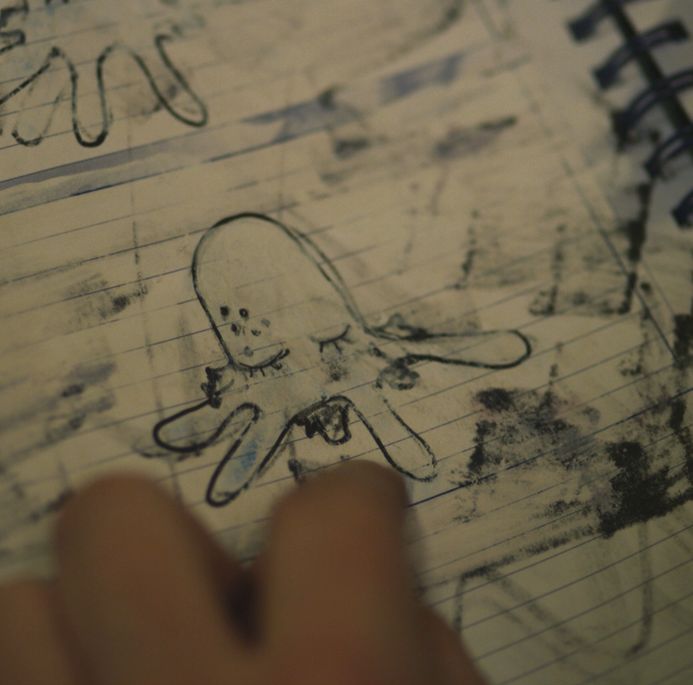 someone is drawing an octopus on a notebook