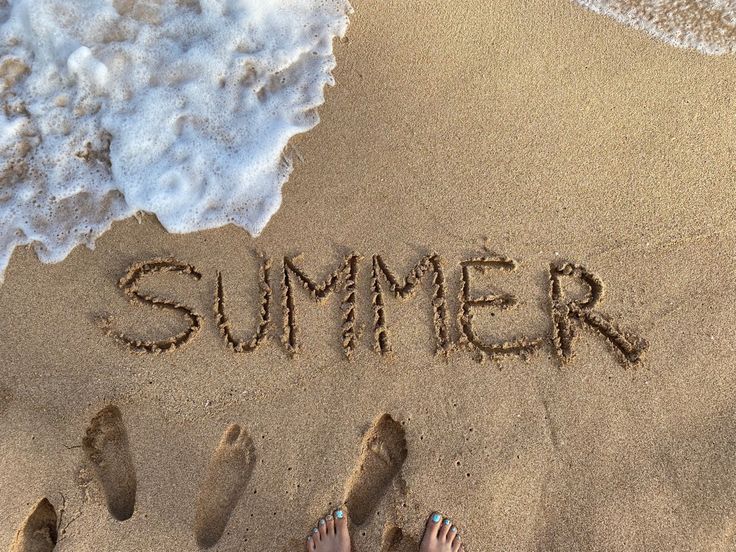 two people standing in the sand with their feet up and writing on the beach that says summer