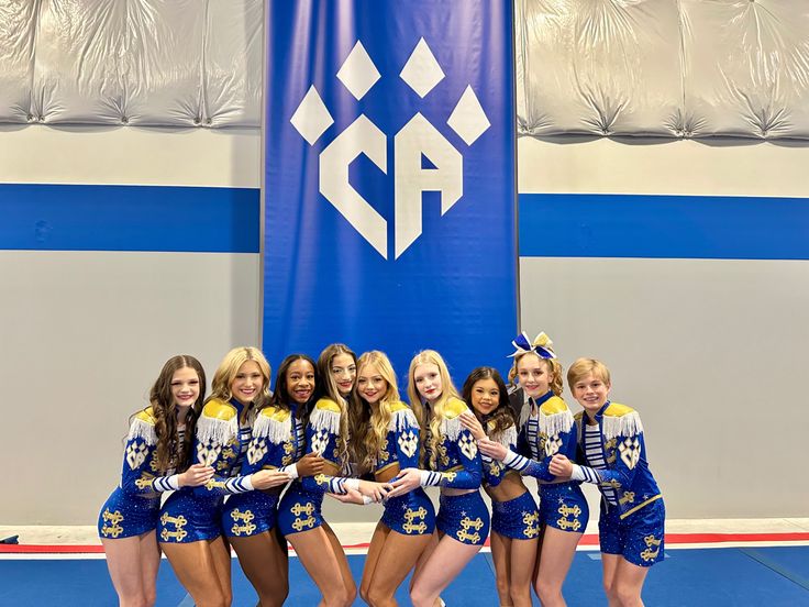 a group of cheerleaders posing for a photo in front of a blue and white banner