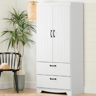 a white armoire next to a chair and potted plant