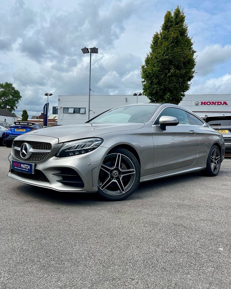 a silver mercedes s - class coupe parked in a parking lot with other cars behind it