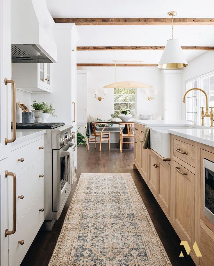 an instagram photo of a kitchen with white cabinets and wood floors, along with a rug on the floor