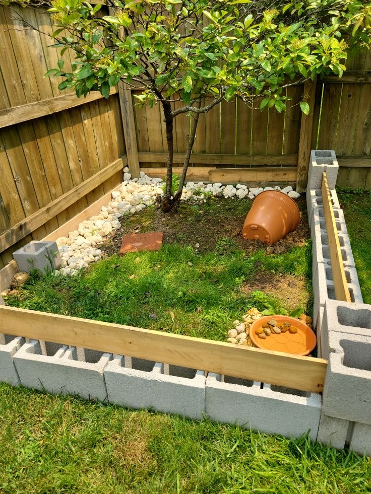 a small garden with grass and rocks in the middle, next to a wooden fence