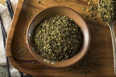 a wooden bowl filled with dried herbs on top of a table next to a towel