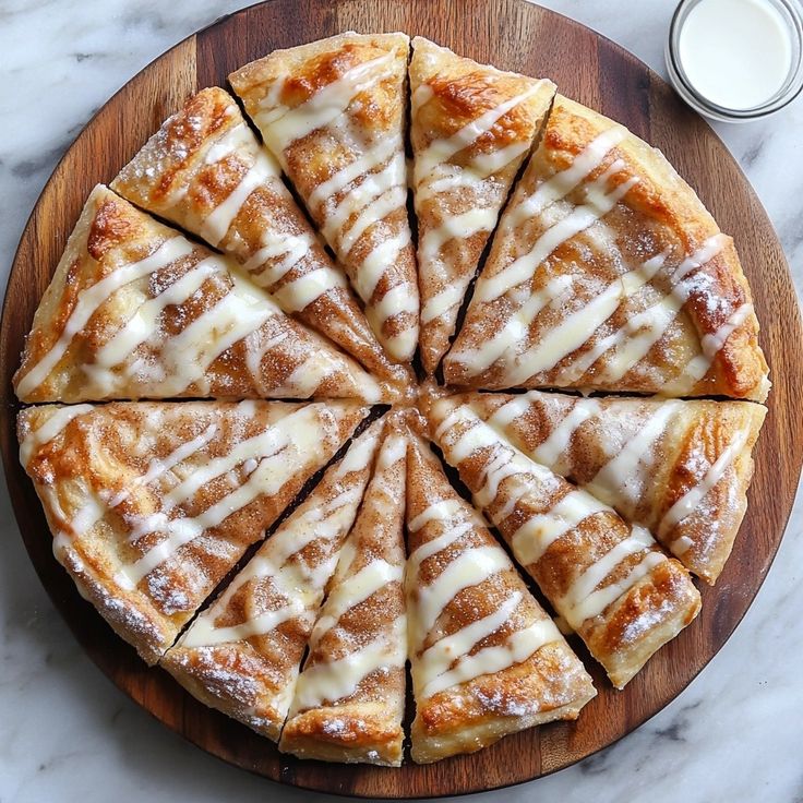 a wooden platter topped with sliced pizza on top of a table next to a glass of milk