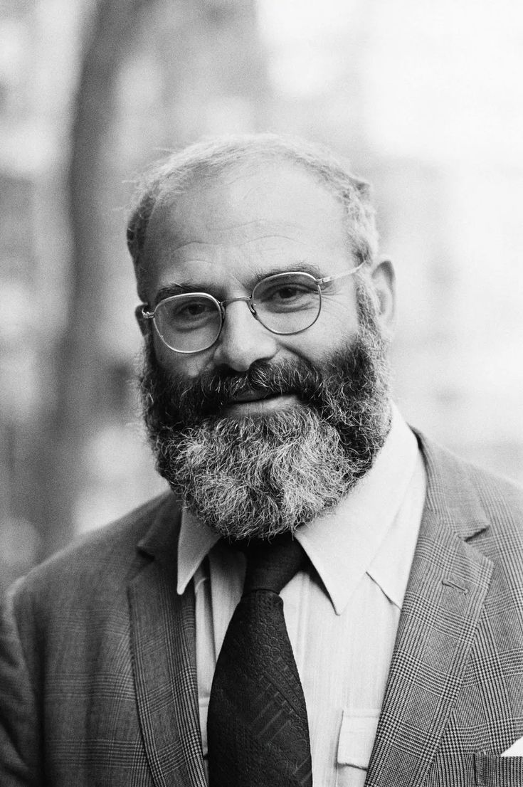 a black and white photo of a man with a beard in a suit jacket and tie