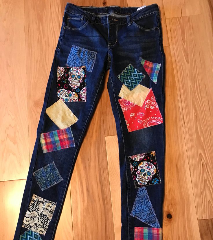 a pair of jeans with patchwork on them sitting on top of a wooden floor