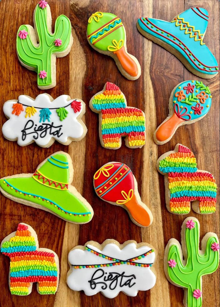 some decorated cookies are sitting on a wooden table with cactuses and sombreros