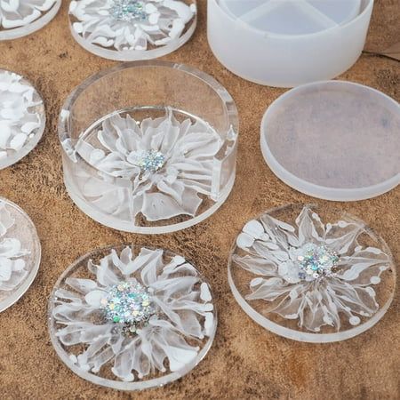 six clear glass plates with flower designs on them and one white vase in the background