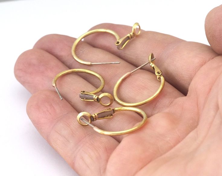 a hand holding three pairs of gold hoop earrings