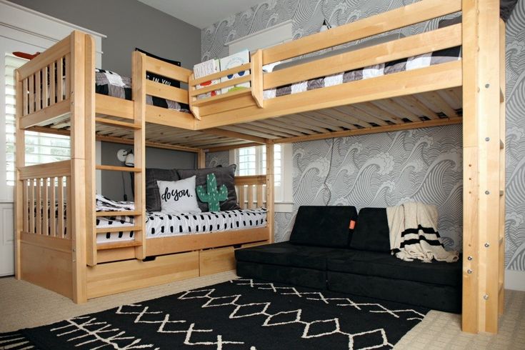 a bedroom with bunk beds and a futon sofa in the corner, along with a rug on the floor