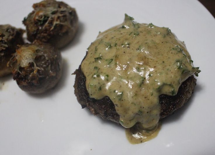 a white plate topped with meat covered in gravy next to three other food items