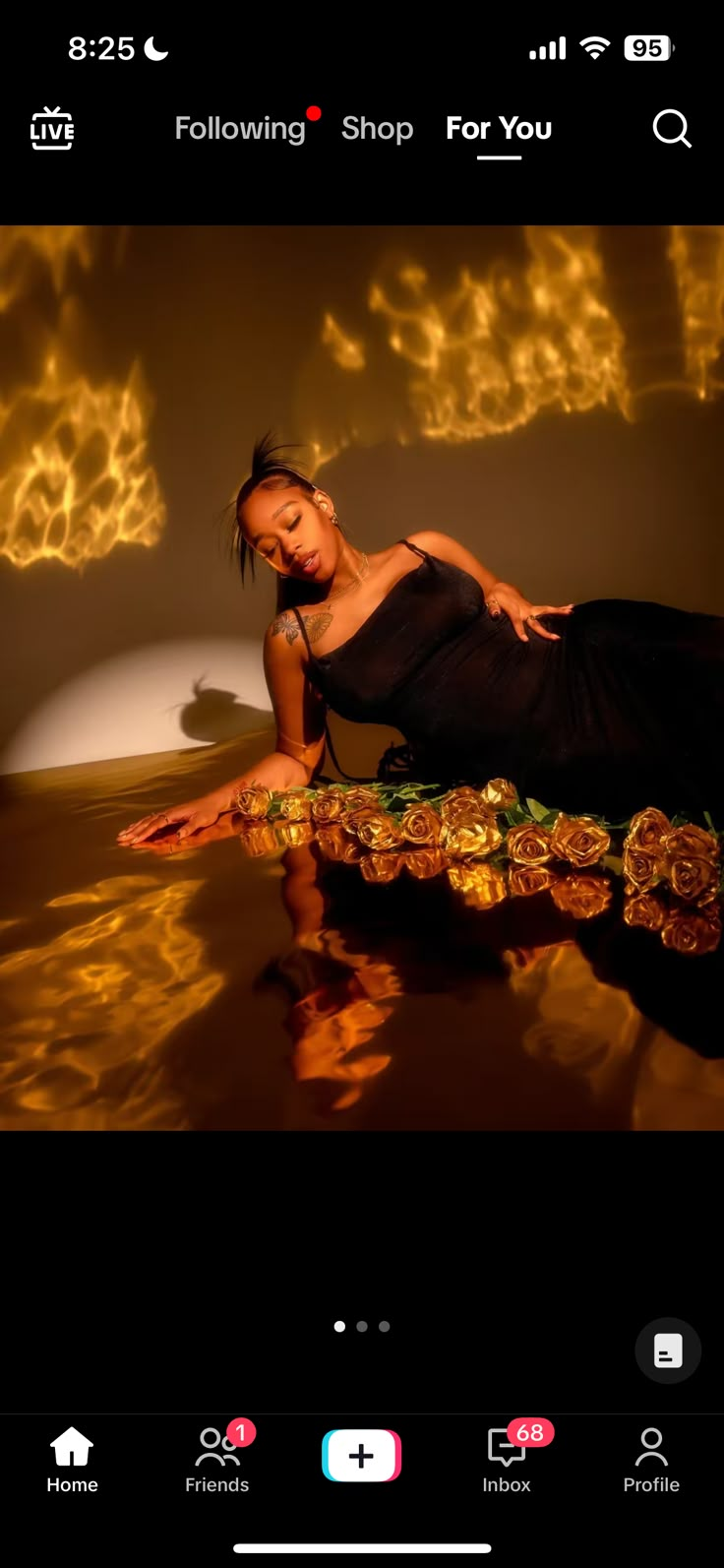 a woman in black dress sitting on top of a table with an orange light behind her