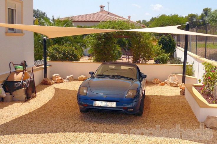 a blue sports car parked in front of a white house with a beige awning