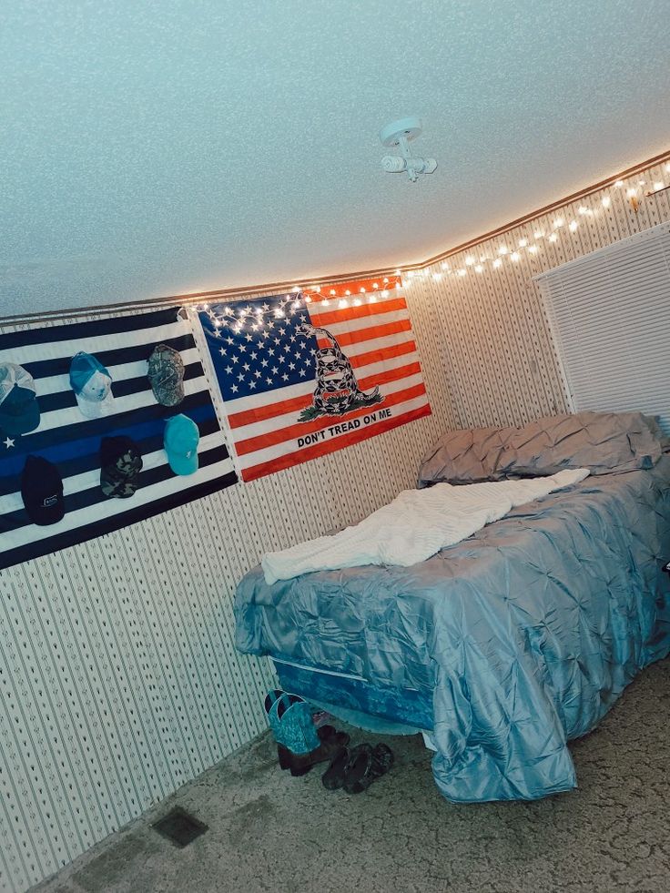 a bedroom with an american flag hanging on the wall and a bed covered in blue sheets