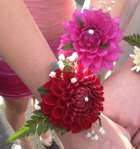 two bridesmaids hold their bouquets with red and white flowers on them,