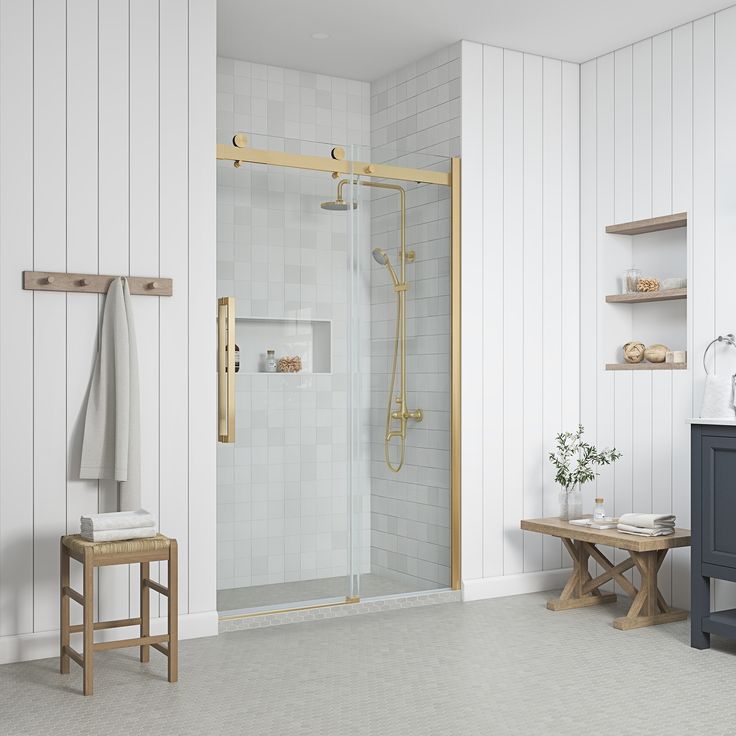 a bathroom with white walls and flooring has a wooden bench in front of the shower