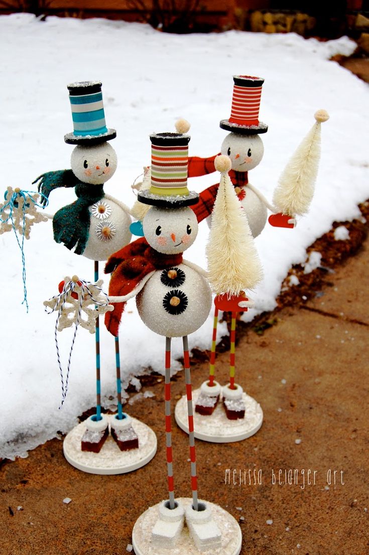 three snowmen with hats and scarves are standing in the snow