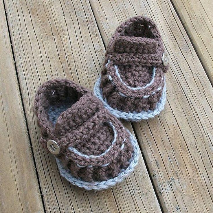 a pair of crocheted baby shoes sitting on top of a wooden floor