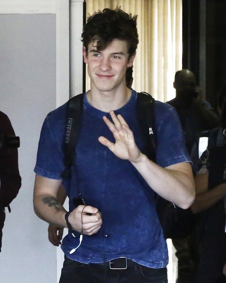 a young man in blue shirt holding his hand up