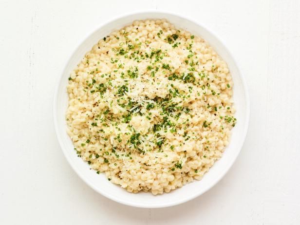 a white bowl filled with rice and parsley on top of a white tablecloth