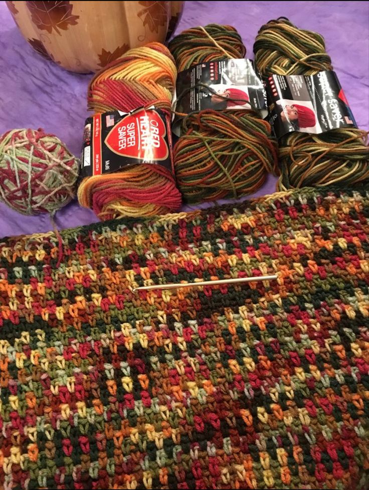 several balls of yarn sitting on top of a bed next to a crochet bag