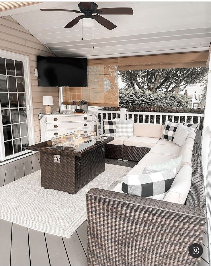 an outdoor living area with wicker furniture and a flat screen tv mounted on the wall