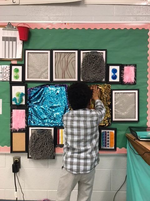 a young boy is working on some art work in front of a green wall with pictures