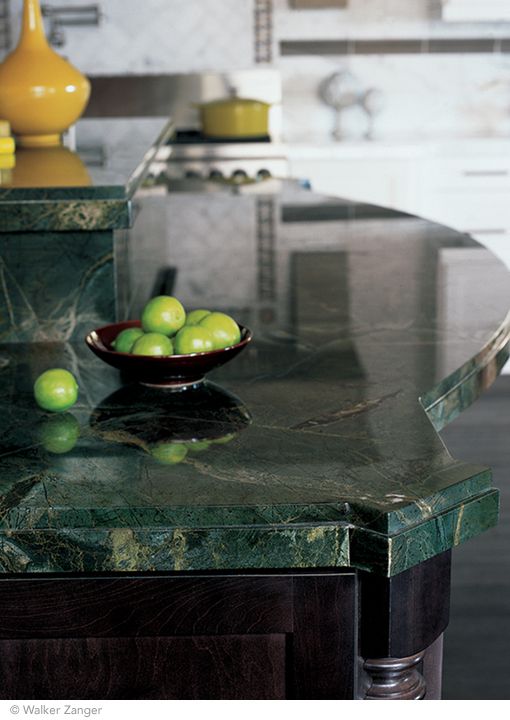 a marble counter top with green apples in a bowl sitting on it's side