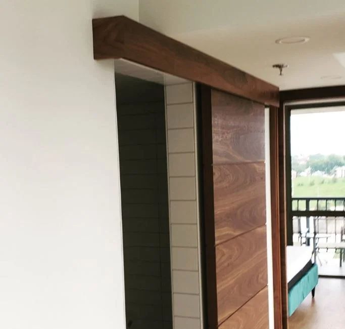 an open door leading to a balcony with sliding glass doors and wood trimmings