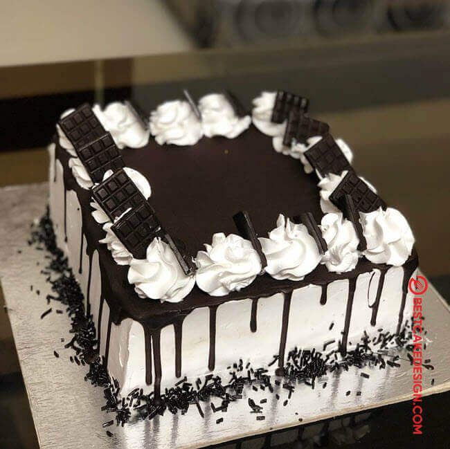 a black and white cake with chocolate icing on it sitting on a counter top