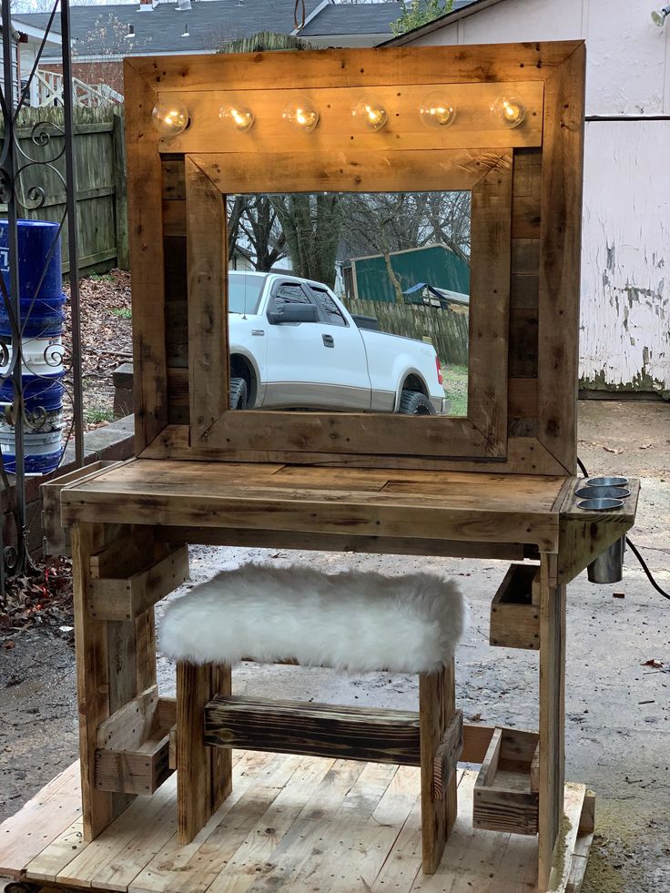 a wooden table with a mirror on top of it next to a white pickup truck