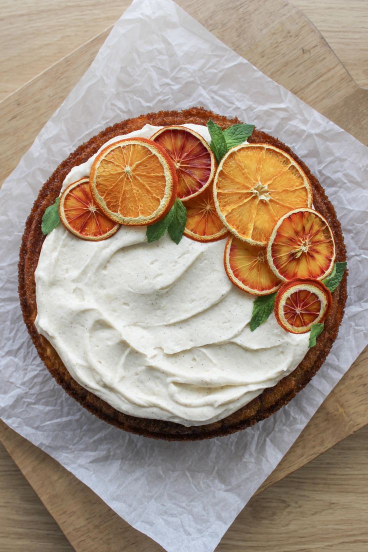 a cake with orange slices on it sitting on top of a piece of wax paper