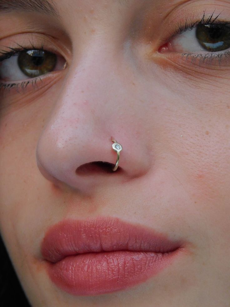 a close up of a person with a nose ring on her nose and piercing in the middle