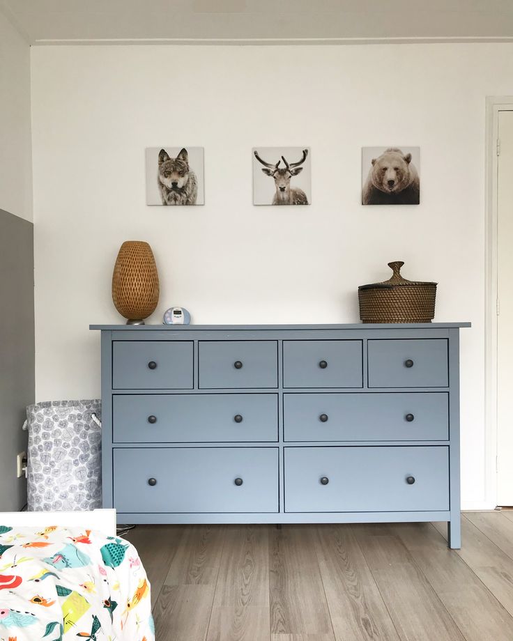 a blue dresser in a white room with pictures on the wall