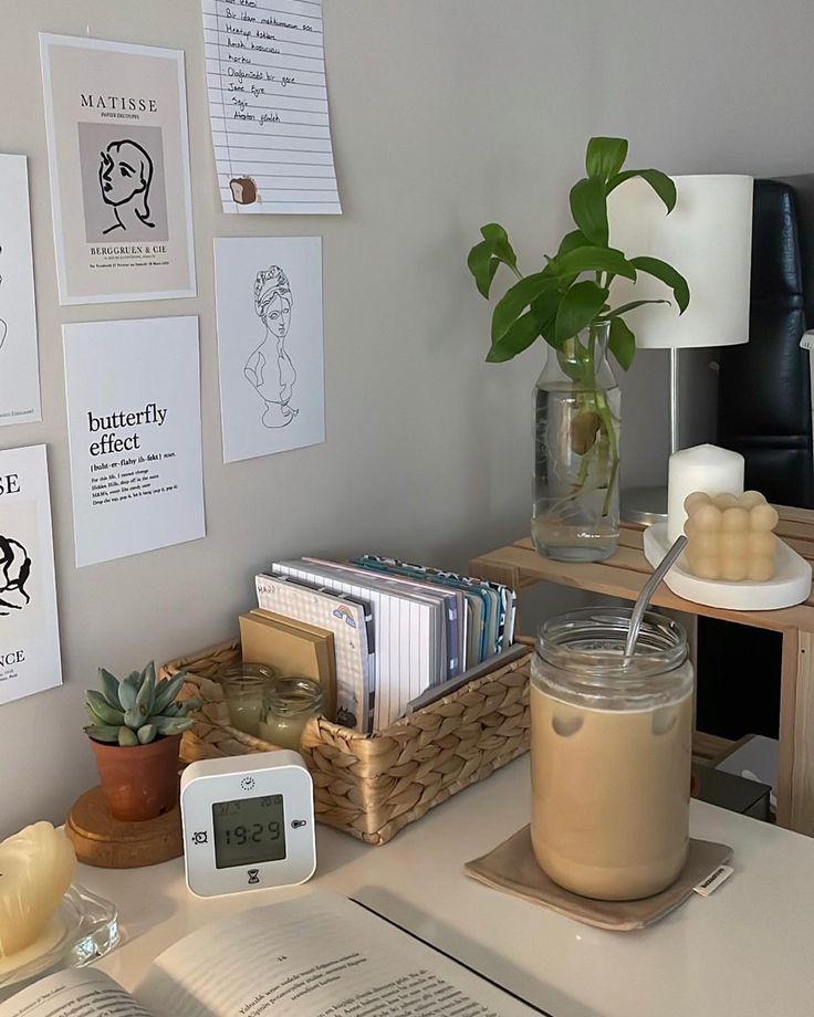 a desk with books, plants and an alarm clock on the table next to it