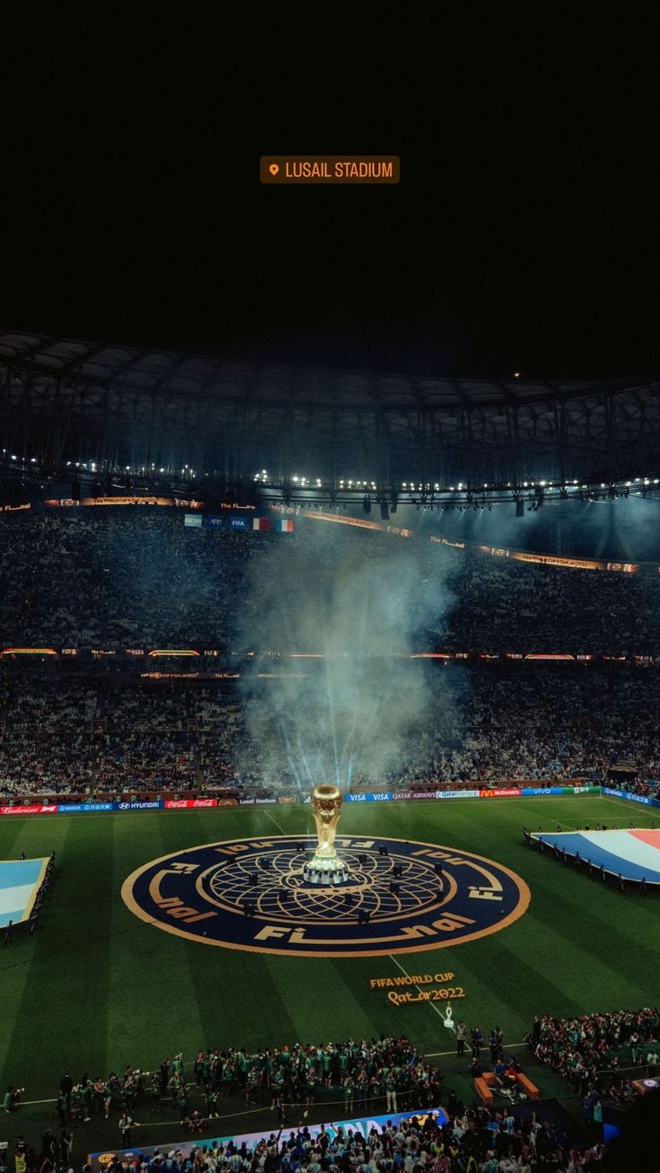 a stadium filled with lots of people watching fireworks in the air and on top of a field