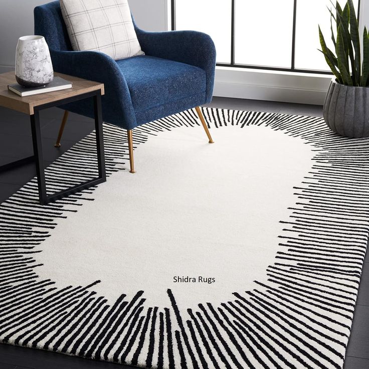 a white rug with black and white lines on it next to a blue chair in front of a window